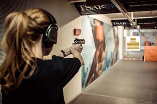Фото девушки с пистолетом, стреляющей по мишеням в боевом тире
